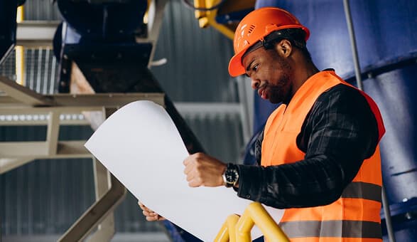Engineer in safety gear checking industrial equipment